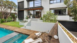 A modern two-story house with a swimming pool, outdoor seating, and a well-maintained garden.