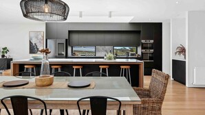 A modern kitchen with a central island, bar stools, and a hanging light fixture.