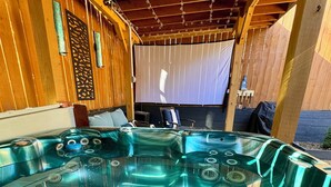 Ett område med ett bubbelbad, träbjälkar och en överbyggd sittplats.