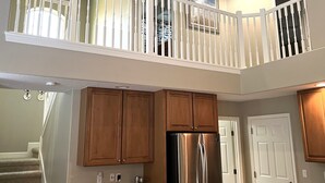 Una cocina con armarios de madera, un refrigerador de acero inoxidable y una puerta blanca.