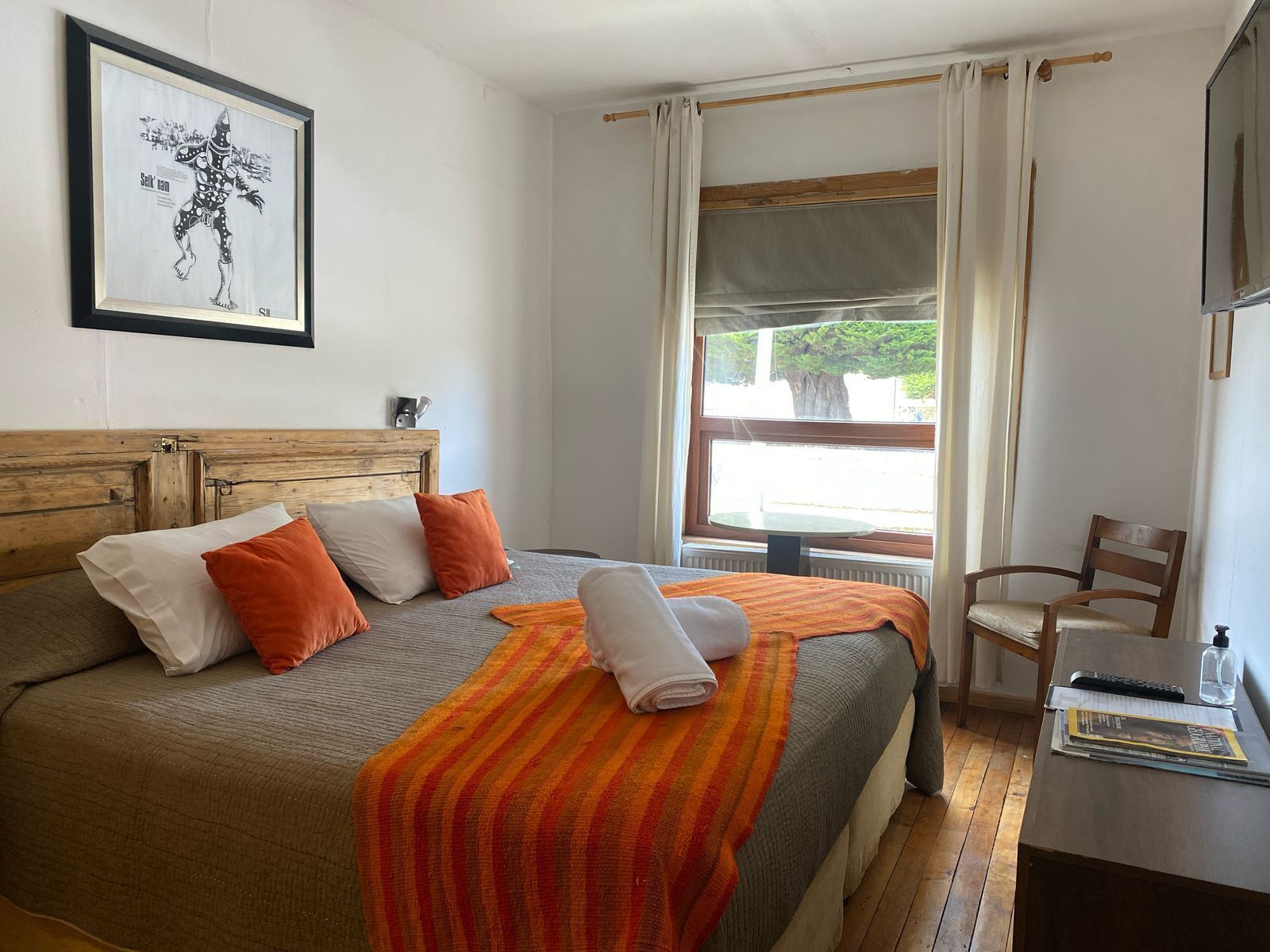 A neatly made bed with a striped blanket, a wooden headboard, and a framed picture on the wall.