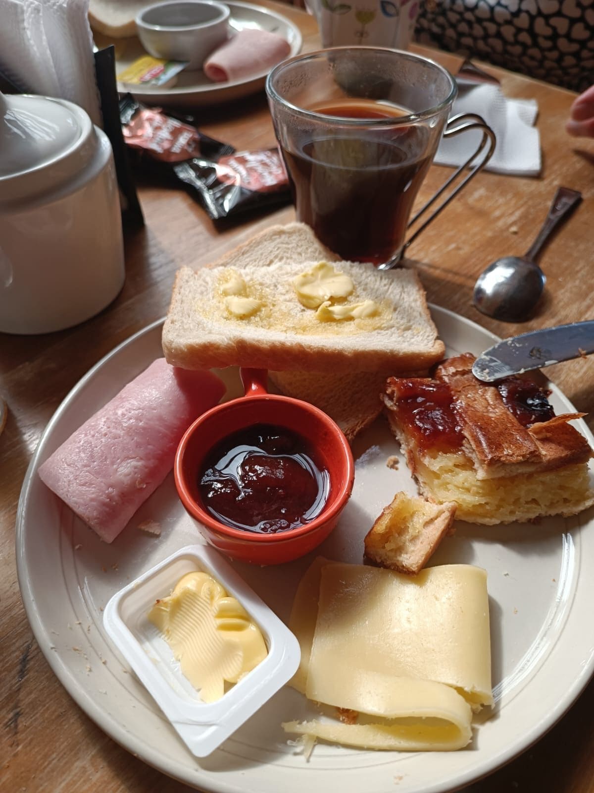 Un plato con tostadas, mermelada, mantequilla y jamón.