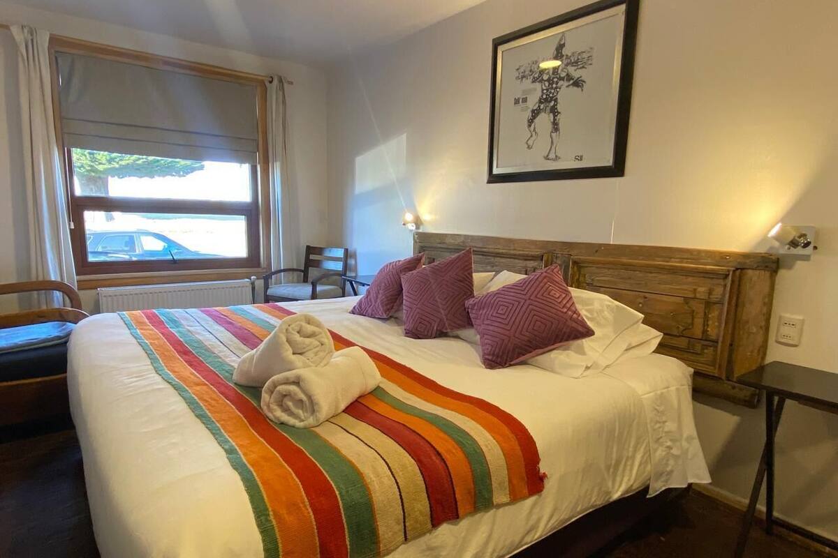 A hotel room with a large bed, a wooden headboard, and a framed picture on the wall.
