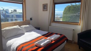 Une chambre à coucher avec un lit, une fenêtre, un radiateur et une chaise noire.