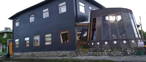 A modern building with a dark facade, multiple windows, and a unique curved glass structure.