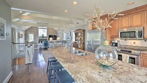 Een ruime keuken met een groot eiland, roestvrijstalen apparatuur en een decoratieve glazen vaas.