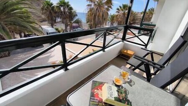 Un balcone con un tavolo, un libro e un bicchiere di succo d'arancia.