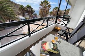 Ein Balkon mit Tisch, Buch und einem Glas Orangensaft.