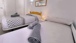 Camera d'albergo con due letti, una testiera in legno, un comodino con una lampada e uno specchio a parete.