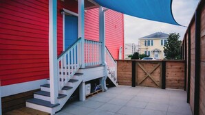 A red building with a white staircase and a wooden deck. - The Board House "Longboard" (Galveston)