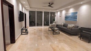 Ein geräumiges Wohnzimmer mit einem großen Sofa, einem Couchtisch und einem an der Wand montierten Fernseher.