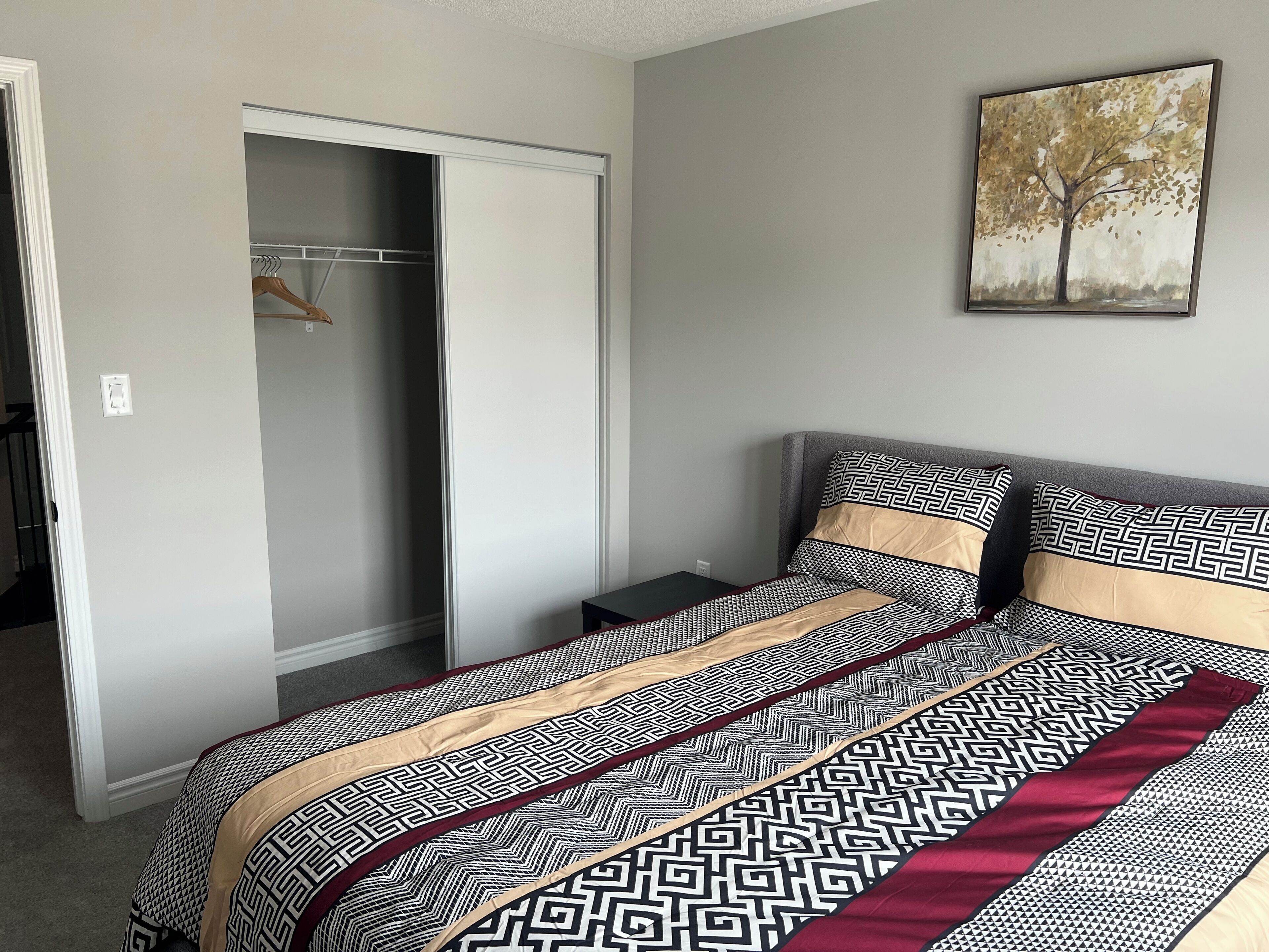 Un dormitorio con cama, armario y un cuadro en la pared.