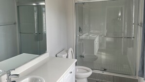 Une salle de bain moderne avec une douche à parois de verre, un lavabo blanc et des toilettes.