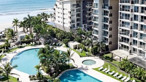 Un complexe hôtelier doté de plusieurs piscines, offrant une vue sur la plage et comprenant des bâtiments modernes.