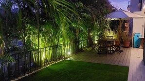 Une terrasse avec une plateforme en bois, une table et des chaises, ainsi qu’un espace salon abrité.