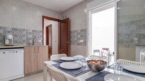 A modern kitchen with a dining area, featuring a coffee machine, a sink, and a dining table set for four. - Beautiful home in Conil de la Frontera (Conil de la Frontera)
