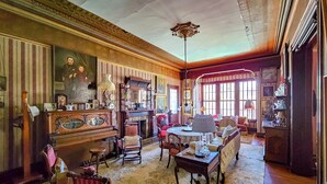 A spacious room with a large fireplace, multiple seating areas, and a high ceiling with ornate moldings. - The JD Hyde Historic Inn (Visalia)
