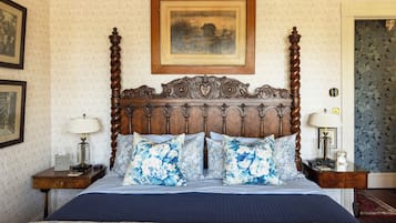Una cama bien hecha con ropa de cama floral, un cabecero de madera y dos mesitas de noche con lámparas.