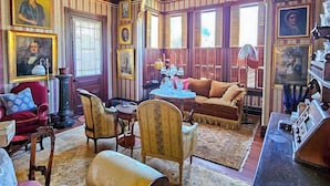 A room with a wooden ceiling, patterned wallpaper, and a variety of furniture including a sofa, chairs, and a table. - The JD Hyde Historic Inn (Visalia)