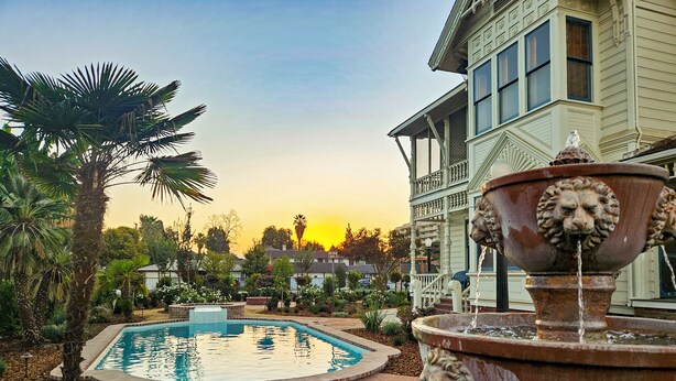 A fountain with a lion head, a pool, and a brick pathway. - The JD Hyde Historic Inn (Visalia)