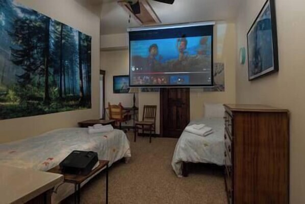 Een hotelkamer met twee bedden, een aan de muur bevestigde televisie en een schilderij.