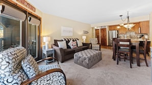 A living room with a sofa, ottoman, and a dining area with a table and chairs. - Cv112c-2 (Copper Mountain)