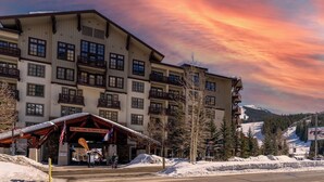 A multi-story hotel with balconies and a ski resort in the background. - Cv112c-2 (Copper Mountain)