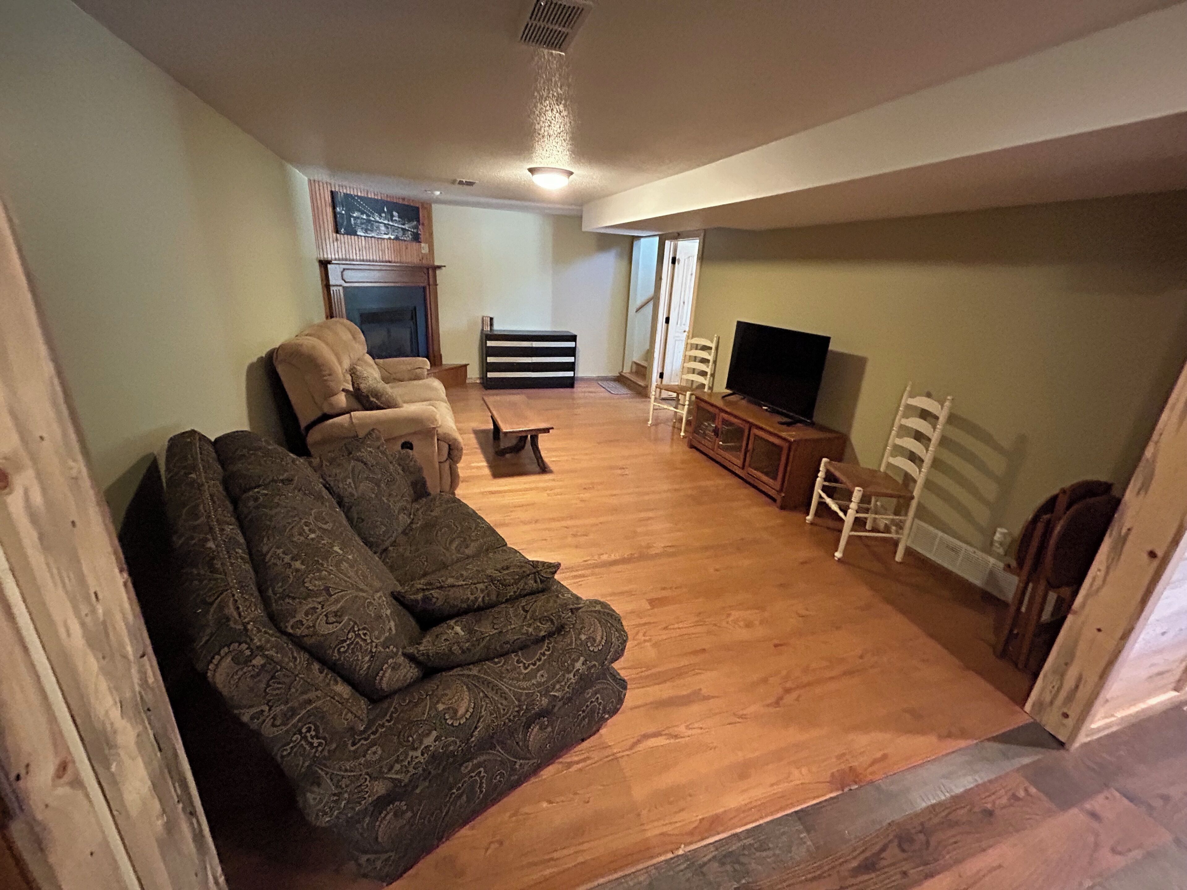 A living room with a sofa, chairs, a television, and a fireplace.