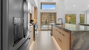 Una cocina moderna con un refrigerador de acero inoxidable, armarios de madera y una encimera de mármol.