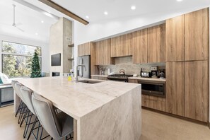 A modern kitchen with a large island, wooden cabinets, stainless steel appliances, and a view of the outdoors. - Iwtck4 (Keystone)
