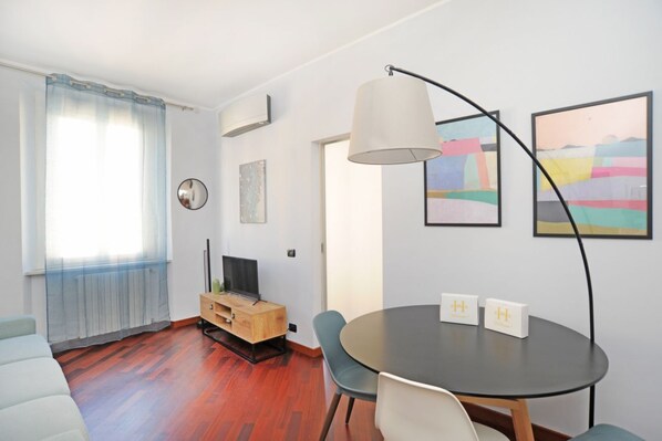 Un salon moderne avec une table ronde, un canapé, un téléviseur et des œuvres d’art accrochées aux murs.