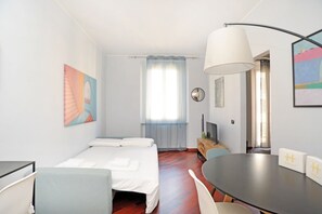 Une chambre d’hôtel équipée d’un lit, d’un bureau, d’une chaise, d’une table, d’une lampe et d’œuvres d’art accrochées aux murs.