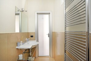 Une salle de bain avec un lavabo, un miroir, un porte-serviettes et une porte.