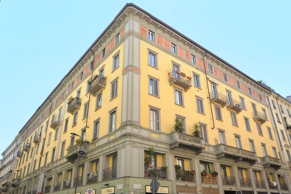 A multi-story building with balconies, a sign indicating a restaurant, and a clear sky.