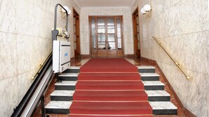 Una escala de marbre amb una catifa vermella que condueix a una porta doble.