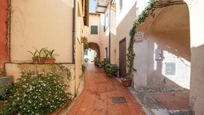 A narrow alleyway with brick flooring, potted plants, and a sign reading "VIA DANTE". - Amazing apartment in Costarainera (Costarainera)
