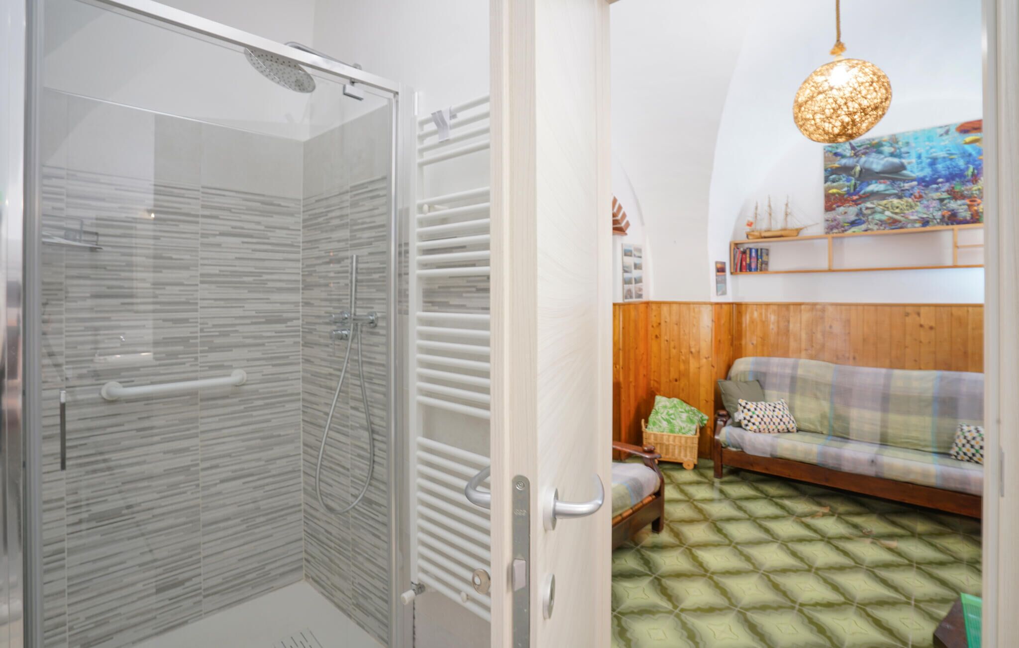 A bathroom with a glass shower enclosure and a wooden floor.
