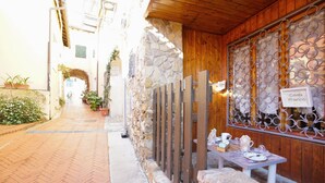 A narrow alleyway with a stone wall on one side and a wooden fence on the other. There is a table with tea set and a sign that reads "Casa Franco". - Amazing apartment in Costarainera (Costarainera)