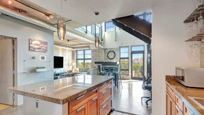 A modern kitchen with a large island, stainless steel appliances, and a dining area with a view. - Luxurious Uptown Denver Loft with Stunning Views (Denver)