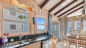 A kitchen with wooden cabinets, a black countertop, a sink, and a dining area with a table and chairs.