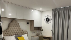 Ein modernes Schlafzimmer mit einem großen Bett, einem Nachttisch, einem Sessel und einem Schreibtisch.