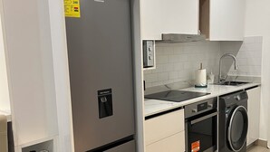 Eine kleine Küche mit integriertem Kühlschrank, Waschmaschine und Spüle.