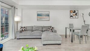 Una sala de estar moderna con un sofá seccional gris, una mesa de comedor con sillas y obras de arte en las paredes.