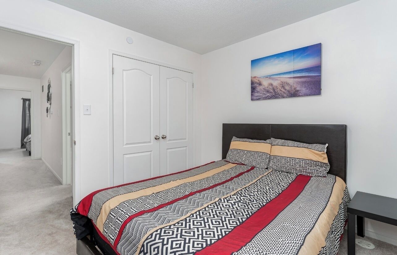 Een slaapkamer met een bed, een schilderij en een deur.
