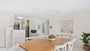 A modern kitchen with white cabinetry, a wooden dining table, and white chairs. - Relax at Riviera (Miami)