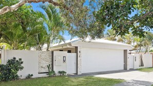A modern house with a garage, a stone wall, and a well-maintained lawn. - Relax at Riviera (Miami)