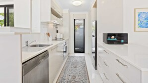 A modern kitchen with white cabinetry, a dishwasher, a microwave, and a stainless steel sink. - Relax at Riviera (Miami)