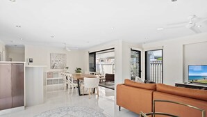 A modern living room with a sofa, a TV, and a dining area with a table and chairs. - Relax at Riviera (Miami)