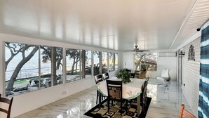 A spacious dining area with a view of the sea, a ceiling fan, and a tiled floor. - Baywatch Waterfront Paradice  8 m to bch, private pier, Sleeps 8 Fenced Dog Area (Gulf Shores)