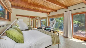 A spacious bedroom with a large bed, a wooden ceiling, and large windows offering a view of the outdoors. - Sea Breeze Dream | Water View, Rooftop Deck, Game Room, Fire Pit & Cozy Backyard! (San Diego)